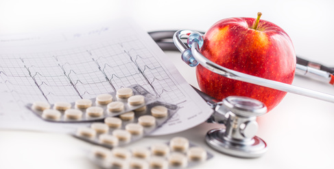 Stethoscope apple and pills on white background.